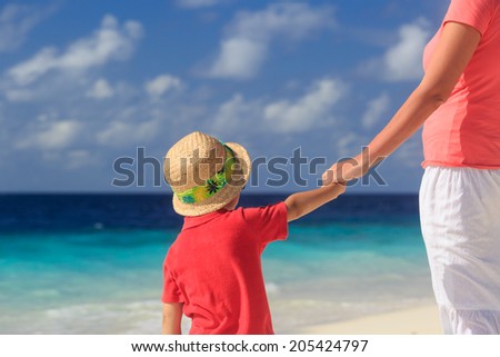 mother and son holding hands on beach vacation