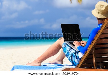 man with laptop on tropical beach vacation