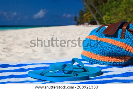 Straw bag, towel and flip flops on a tropical sand beach