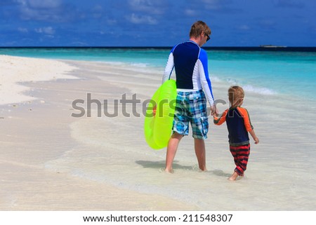 father and son go swimming at tropical beach