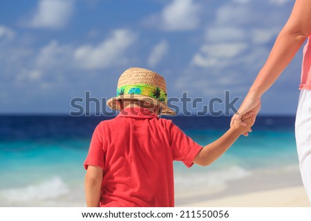 mother and son holding hands on tropical beach vacation