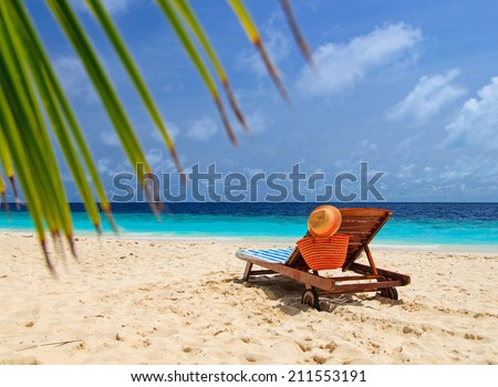 straw hat and bag on a lounge chair at tropical sand beach