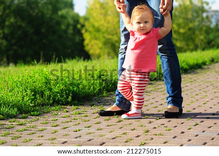 first steps of little girl in summer park