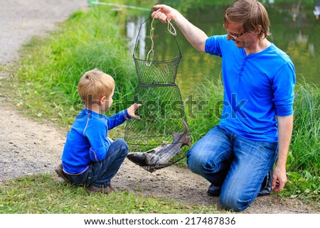 father and son holding fish they caught on the lake