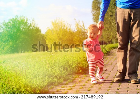 first steps of cute little girl in summer park