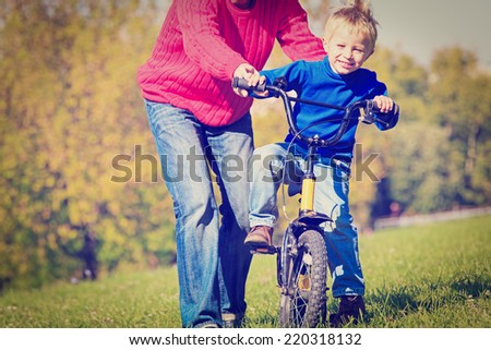 father teaches son to ride bicycle outdoors