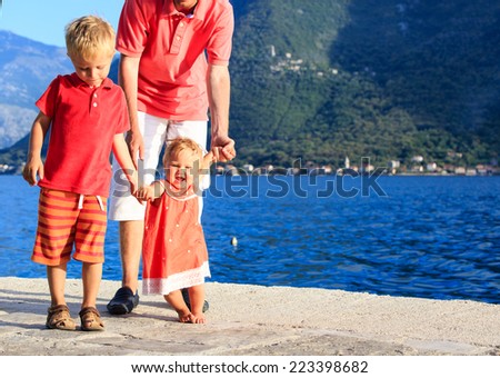 family with little daughter learning to walk on vacation at the sea