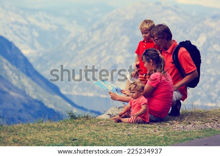family with kids looking at map in mountains