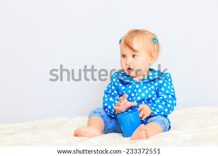 cute little girl with cup of tea indoors
