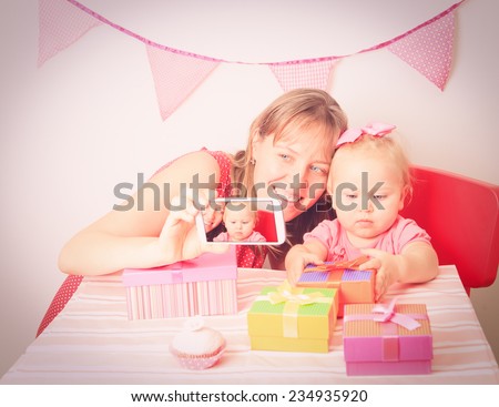 mother and little daughter taking mobile photo at birthday party