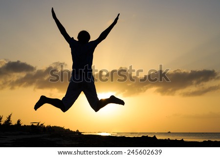 Silhouette of man jumping on sunset beach