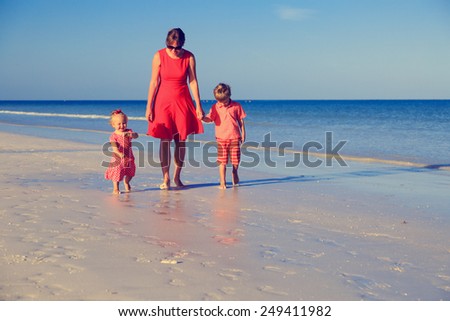 mother and two kids walking on summer beach