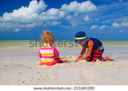 brother and sister playing with sand on tropical beach