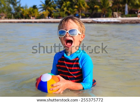 little boy playing ball on summer beach