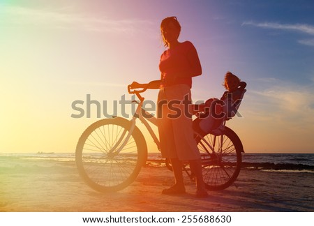 Silhouette of mother and baby biking at sunset beach