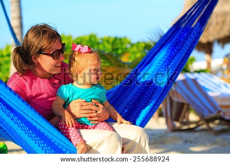 mother and little daughter on beach vacation relaxed in hammock