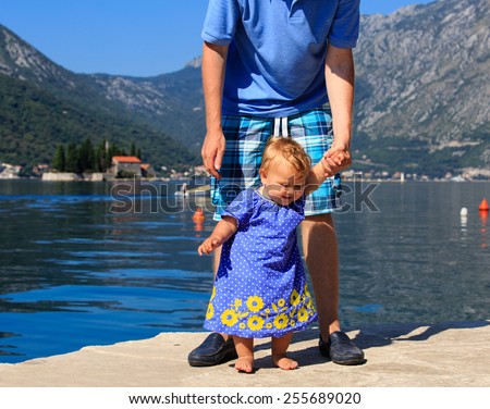 father and little daughter learning to walk on sea vacation