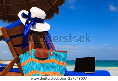 hat, bag and laptop on summer tropical beach