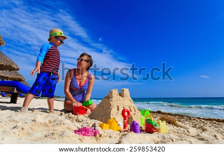 mother and son building sand castle on tropical sand beach