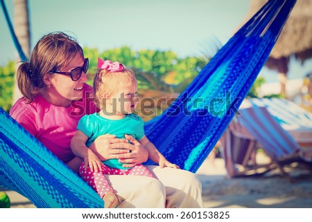 mother and little daughter on beach vacation relaxed in hammock