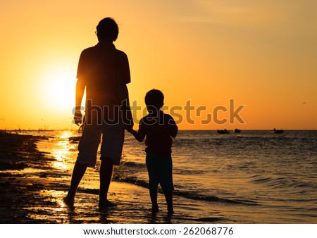 father and son holding hands at sunset sea