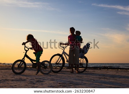 happy mother with two kids biking at sunset
