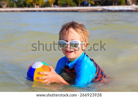happy little boy playing ball on summer beach