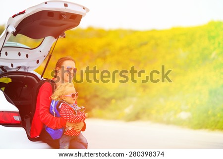 mother and little daughter travel by car in summer nature