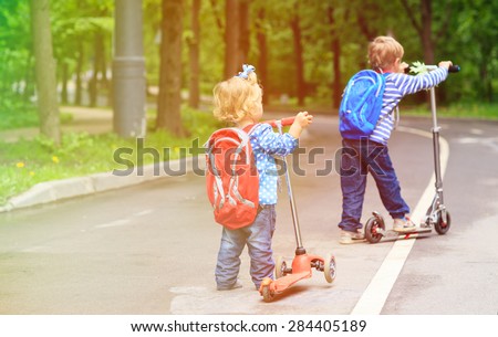 little boy and toddler girl riding scooters in the city, family sport