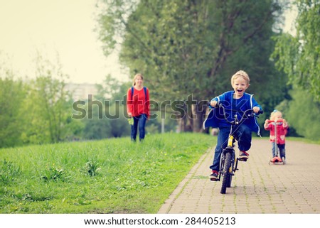 happy kids riding scooter and bike in the park, family sport