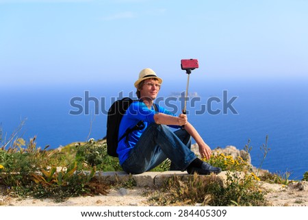 young tourist making selfie photo with stick on mountains travel