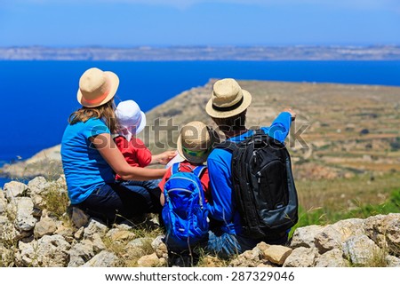 family with two kids looking at map in mountains, family travel