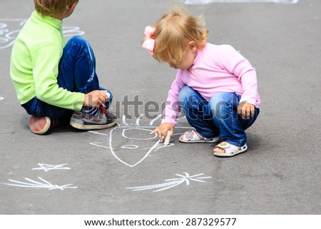 little boy and toddler girl drawing rocket on asphalt, kids outdoor activities