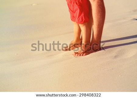 Close up of father and little daughter feet on a tropical beach