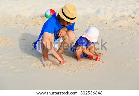 father and little daugther drawing family picture on sand beach