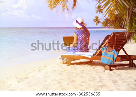 young woman working on laptop at tropical vacation