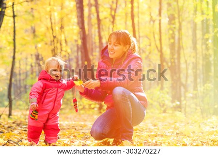 mother and cute little daughter in autumn fall leaves