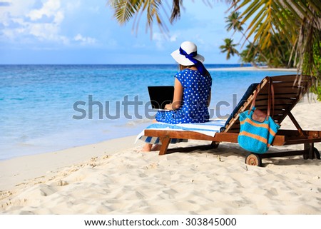 young woman working on laptop at tropical vacation