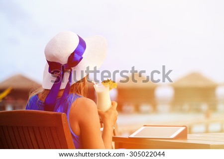 young woman with cocktail and touch pad at luxury tropical resort