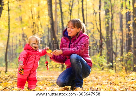 mother and cute little daughter in autumn fall leaves