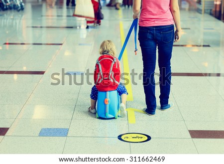 mother and little daugther on suitcase walk in the airport, family travel
