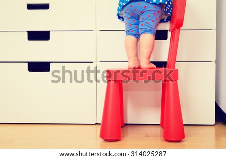 kids safety concept- little girl  climbing on baby chair
