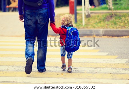 father walking little daughter with backpack to school or daycare