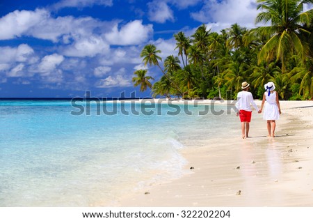 happy loving couple walking on summer tropical beach