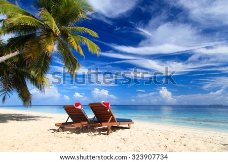 two chair lounges with red Santa hats on tropical summer beach