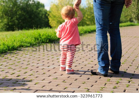 little girl making first steps in the park, kids learning