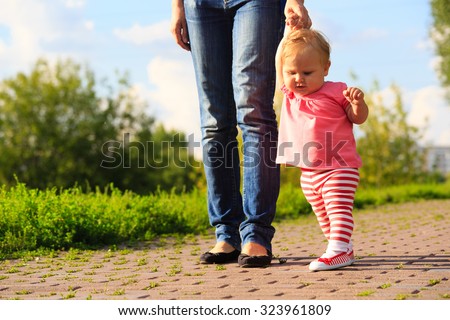 little girl making first steps in the park, kids learning