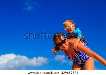 Mother and little son playing airplane on sky at beach