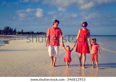 Young family with two kids walking at sand beach