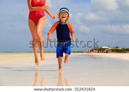 mother and son running in water on tropical beach